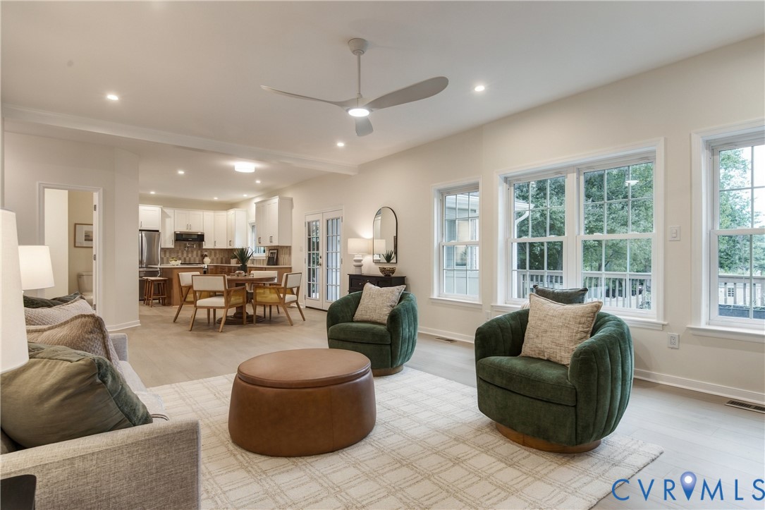Open-concept interior featuring light-toned wood-finish flooring, recessed lighting, a modern ceiling fan, and large windows with multi-pane configuration