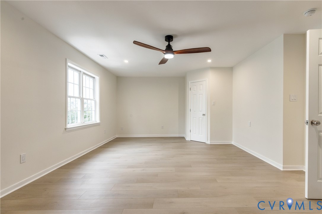 Interior space featuring wood-finish flooring, recessed lighting, a multi-blade ceiling fan with integrated light, and a single-pane window