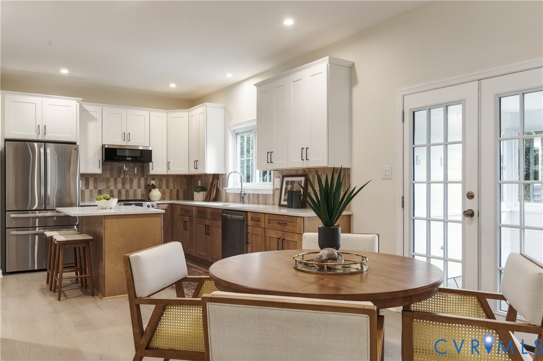 Kitchen featuring dual-tone cabinetry, stainless steel appliances, stone-surface countertops, tile backsplash, and French doors