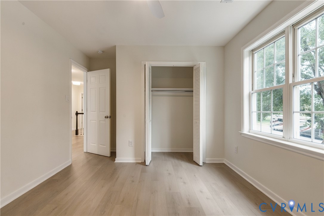 Neutral-toned interior featuring wood-finish flooring, dual-pane windows, a recessed closet with louvered bi-fold doors, and a six-panel interior door
