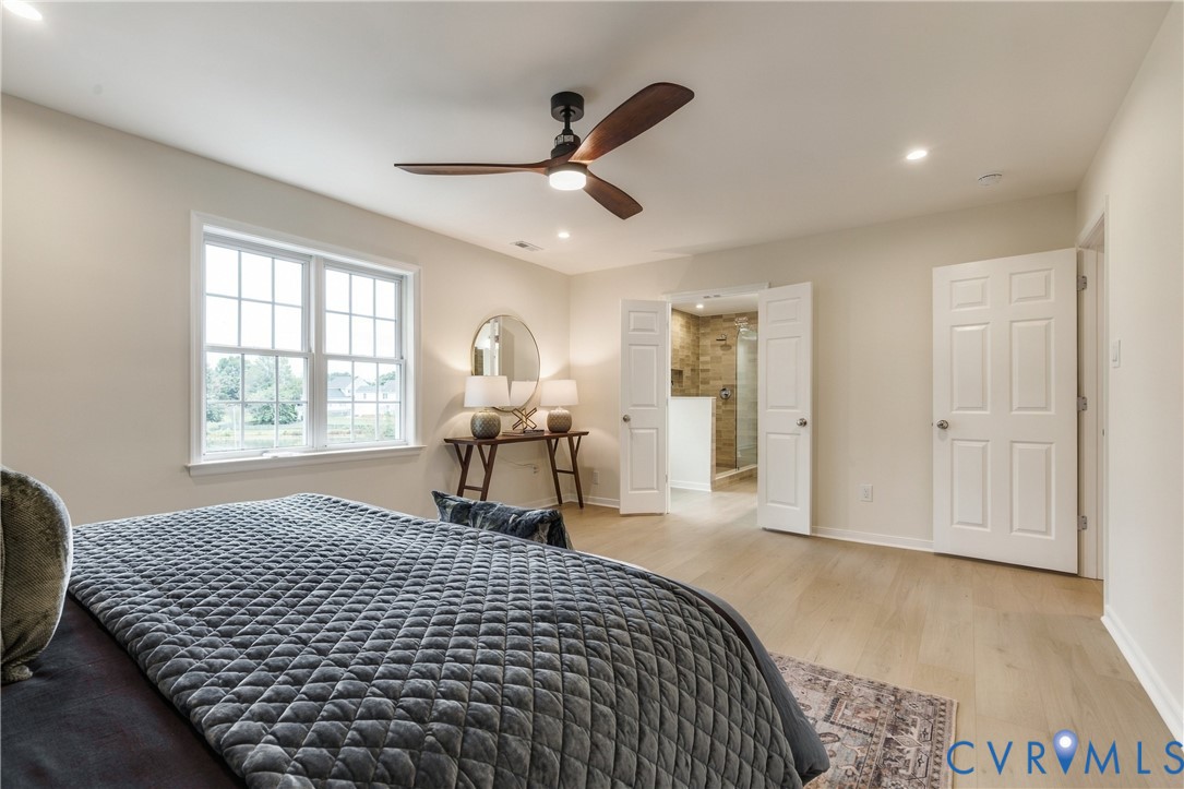 Spacious room featuring light wood-finish flooring, recessed lighting, and a modern ceiling fan with dark wood-tone blades