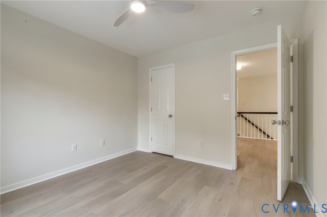 Neutral interior with wood-finish flooring, white paneled doors, and a ceiling-mounted light fixture with an integrated fan
