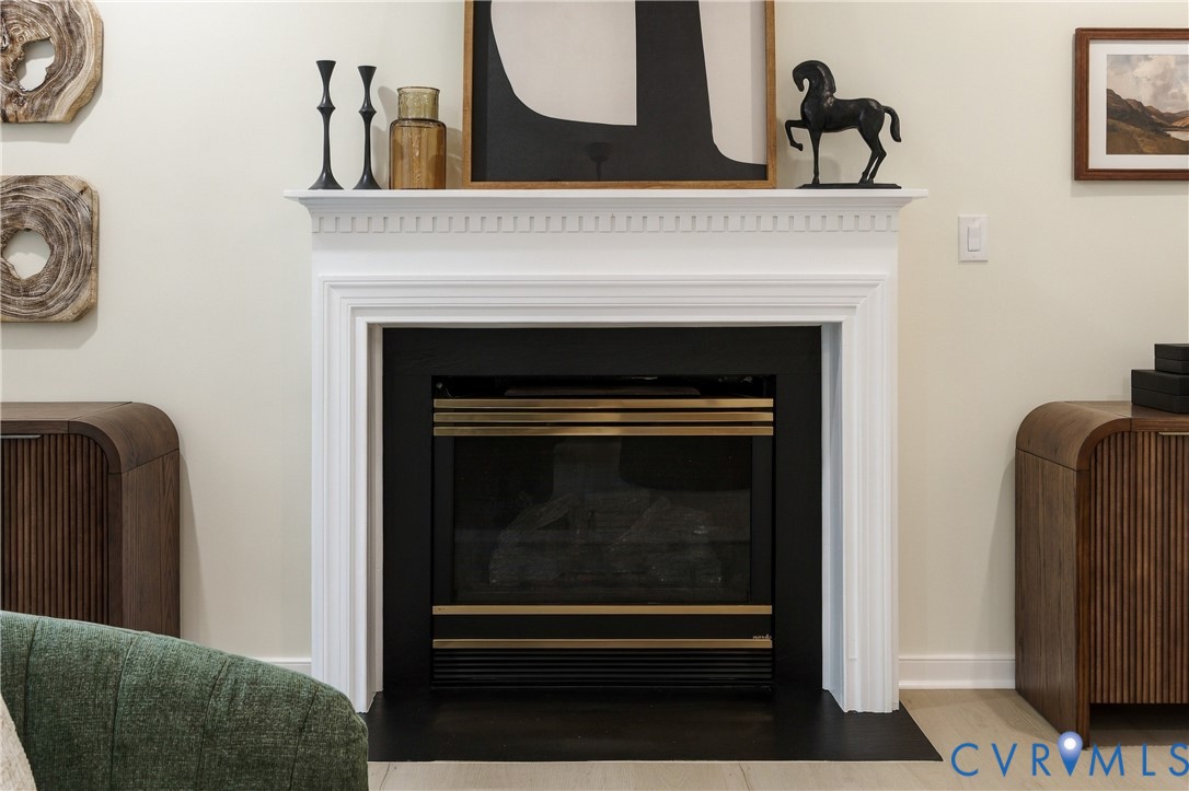 Fireplace featuring a white decorative mantel with dentil molding, black metal surround, and a metal firebox insert