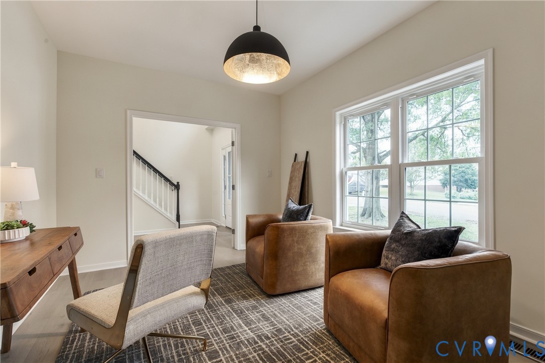 Room featuring wood-finish flooring, dual-pane windows, and a black dome pendant light Room featuring wood-finish flooring, dual-pane windows, and a black dome pendant light