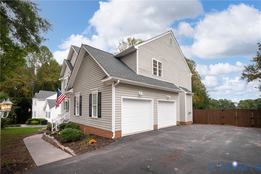 Two-story exterior featuring horizontal siding, a brick water table, an attached two-car garage, and a paved driveway