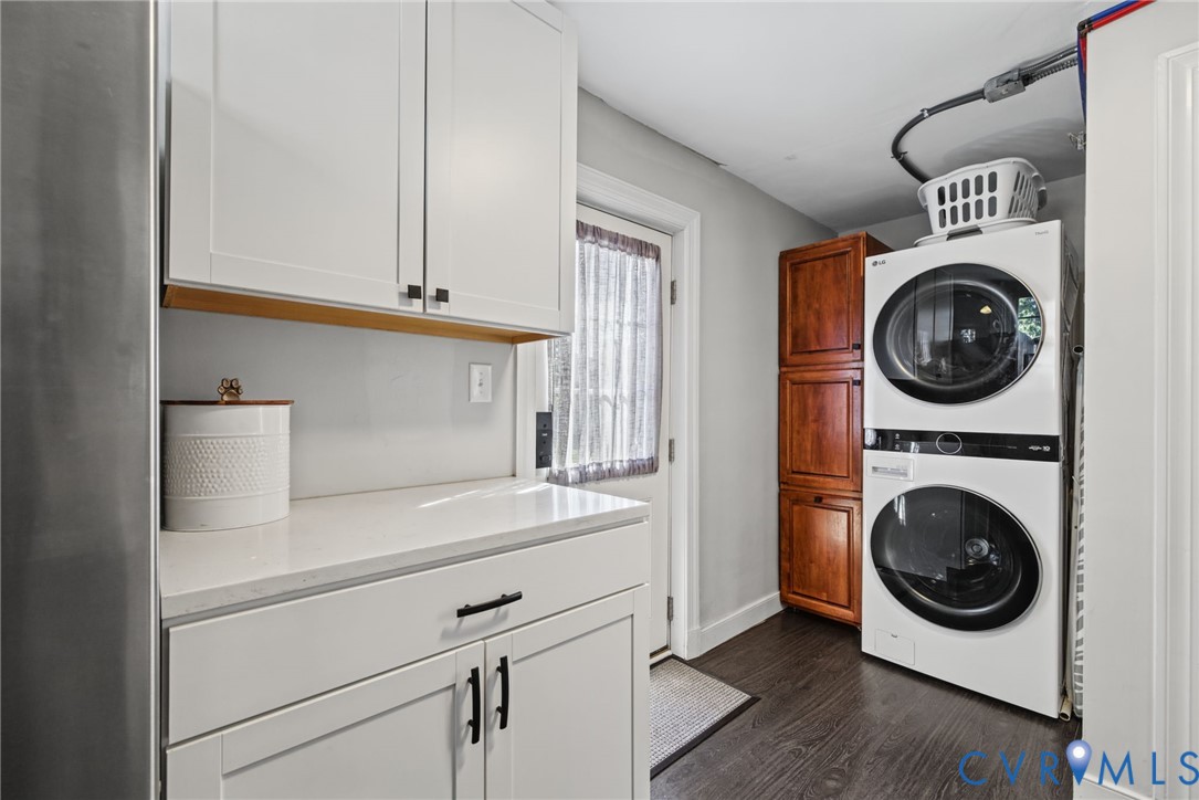 Laundry area featuring white shaker-style cabinetry, quartz countertops, a tall wood-finish storage cabinet, and wood-finish flooring
