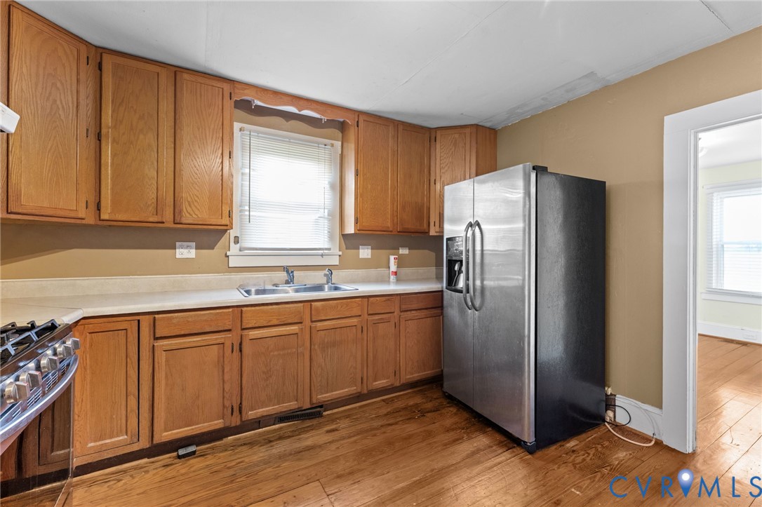 Kitchen featuring wood cabinets, pine floors, double sinks, self standing island & gas range.
