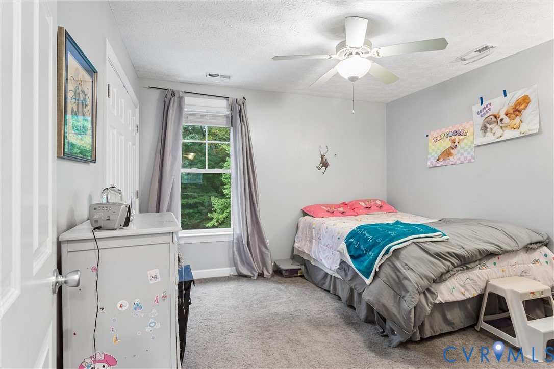 Bedroom featuring neutral wall paint, wall-to-wall carpeting, a multi-pane window, and a ceiling-mounted fan with integrated lighting