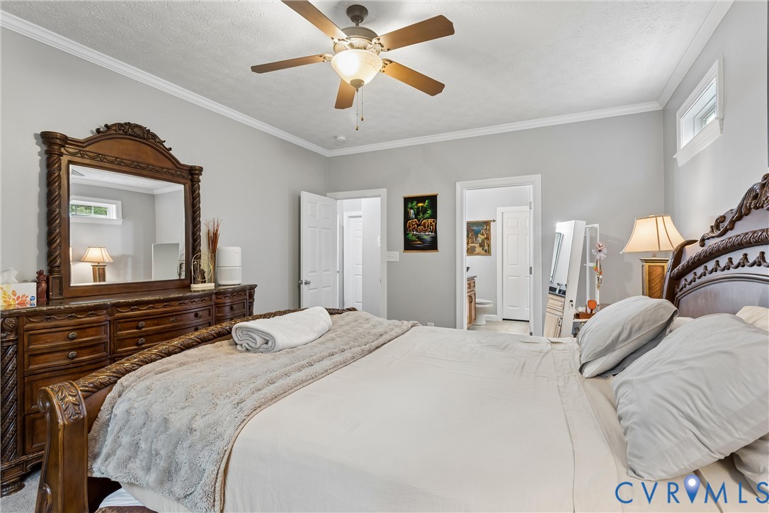 Bedroom featuring crown molding, neutral wall color, and a ceiling fan with integrated lighting