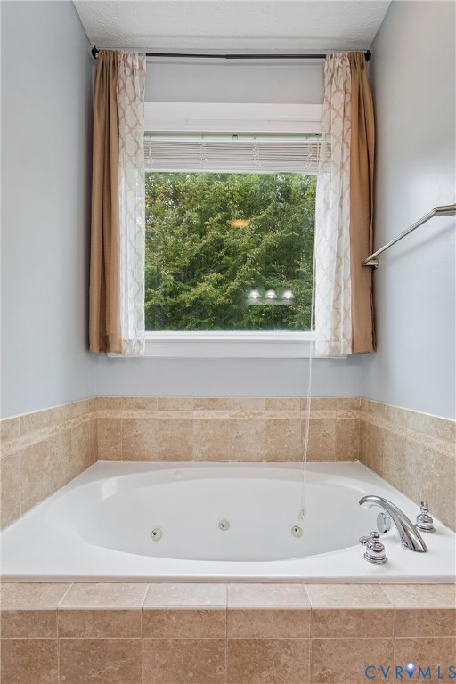 Jetted soaking tub featuring a beige tile surround and polished chrome faucet fixtures