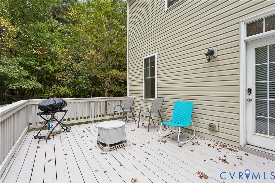 Elevated wood-plank deck featuring light-toned railing, vinyl siding exterior, and exterior wall-mounted lighting