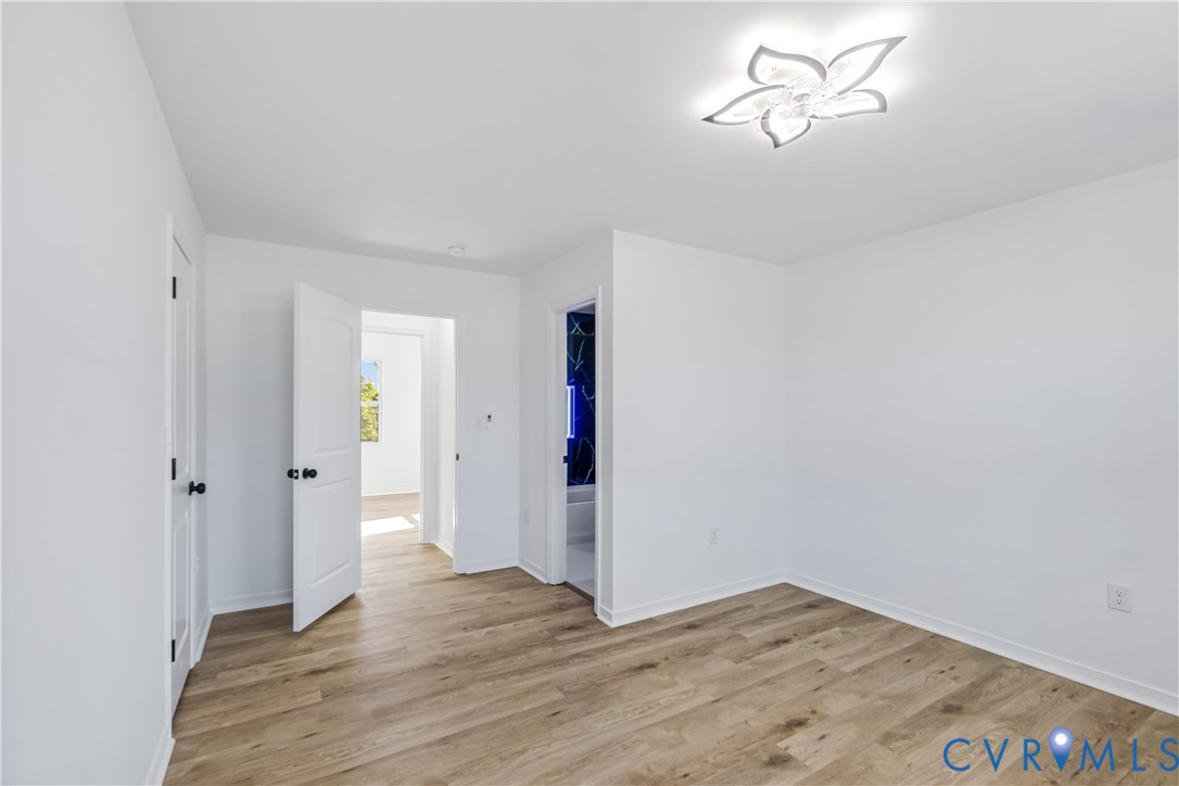 Interior space featuring wood-finish flooring, white walls, and a decorative floral-inspired flush-mount ceiling light fixture