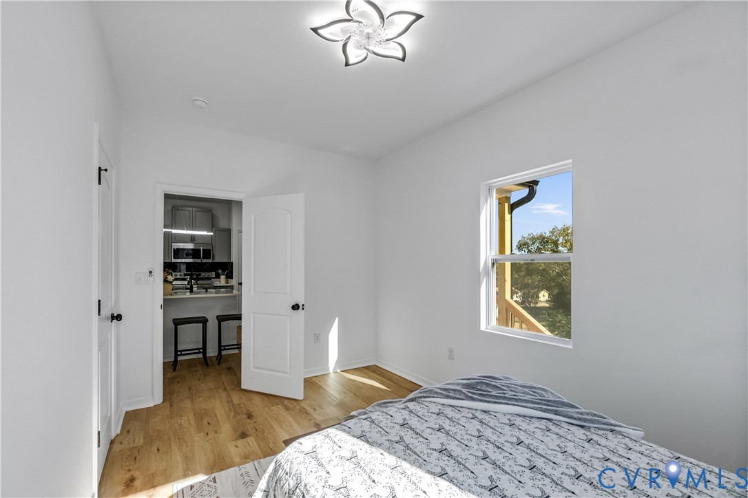 Room featuring wood-finish flooring, a multi-petal flush-mount light fixture, and a single-hung window