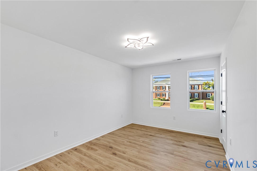 Interior space featuring wood-finish flooring, two double-hung windows, and a decorative flush-mount ceiling fixture