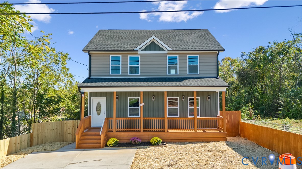 Two-story residence featuring horizontal siding, a covered front porch with wooden railings, a dual-material exterior finish, and a shingled gable roof Two-story residence featuring horizontal siding, a covered front porch with wooden railings, a dual-material exterior finish, and a shingled gable roof