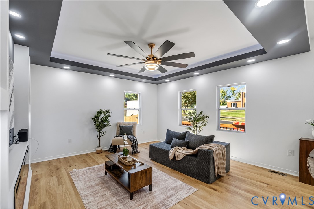 Tray ceiling featuring a dark-toned perimeter, recessed lighting, multi-blade ceiling fan, and light-toned wood-finish flooring