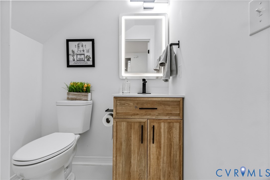 Wood-finish vanity with a rectangular sink, matte black hardware, integrated light-up mirror, and minimalist faucet