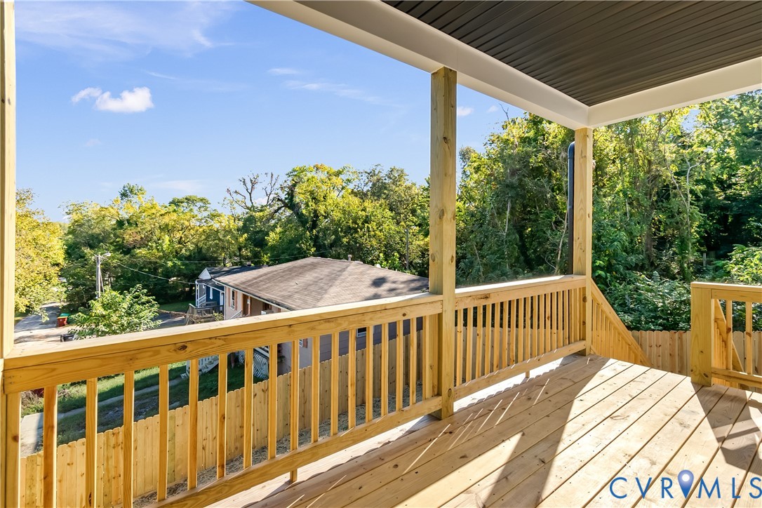 Elevated wood deck featuring vertical wood balusters, a covered ceiling, and natural wood flooring