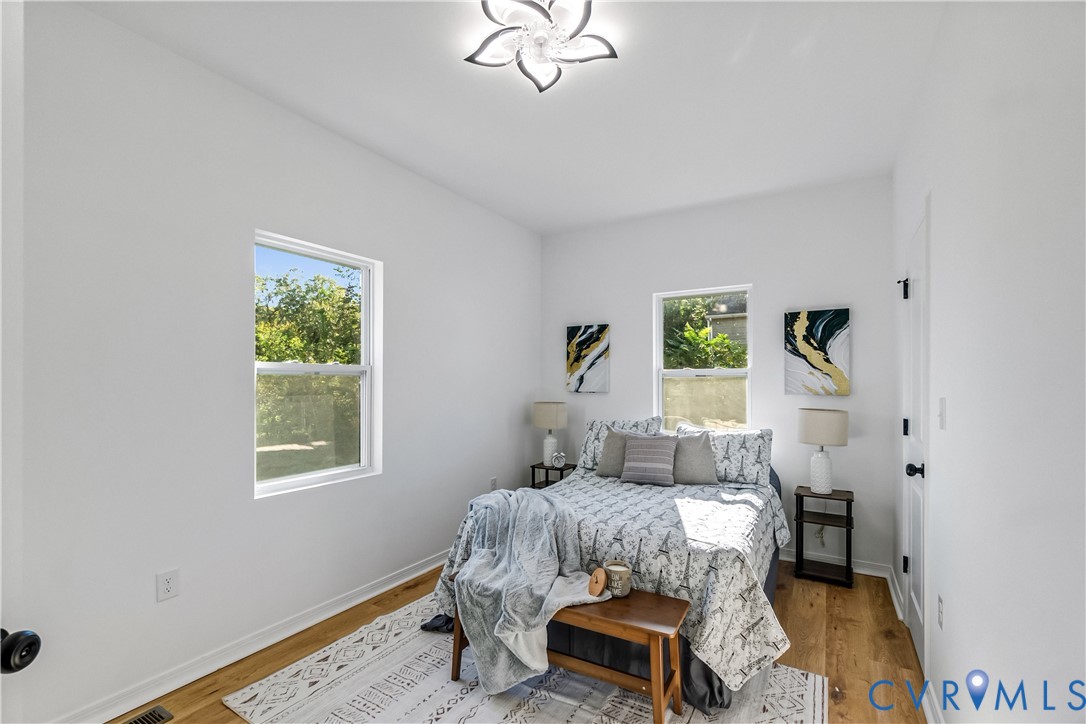 Room featuring wood-finish flooring, two double-pane windows, and a decorative floral-inspired ceiling fixture