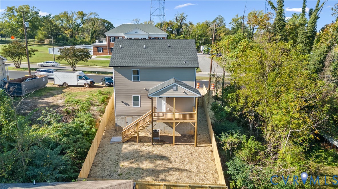 Two-story residence featuring light-toned horizontal siding, a gabled roof, an elevated rear porch with wooden railings, and a fenced backyard