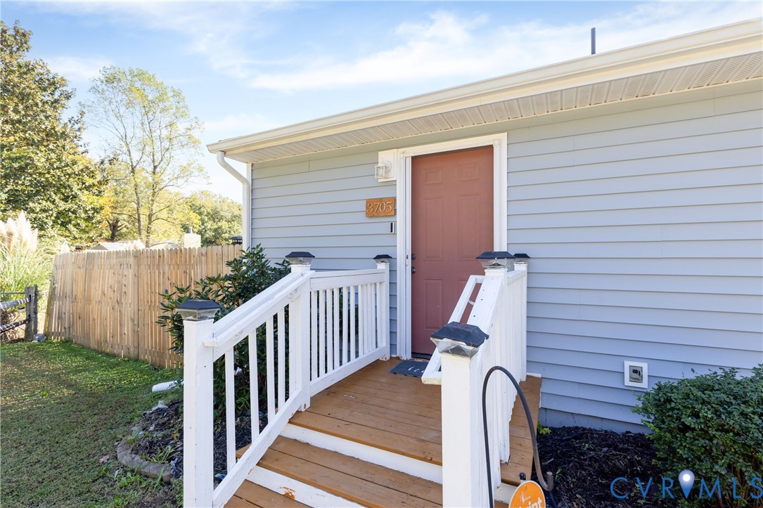 Exterior entrance featuring horizontal lap siding, wood-finish steps, and white balustrade railing