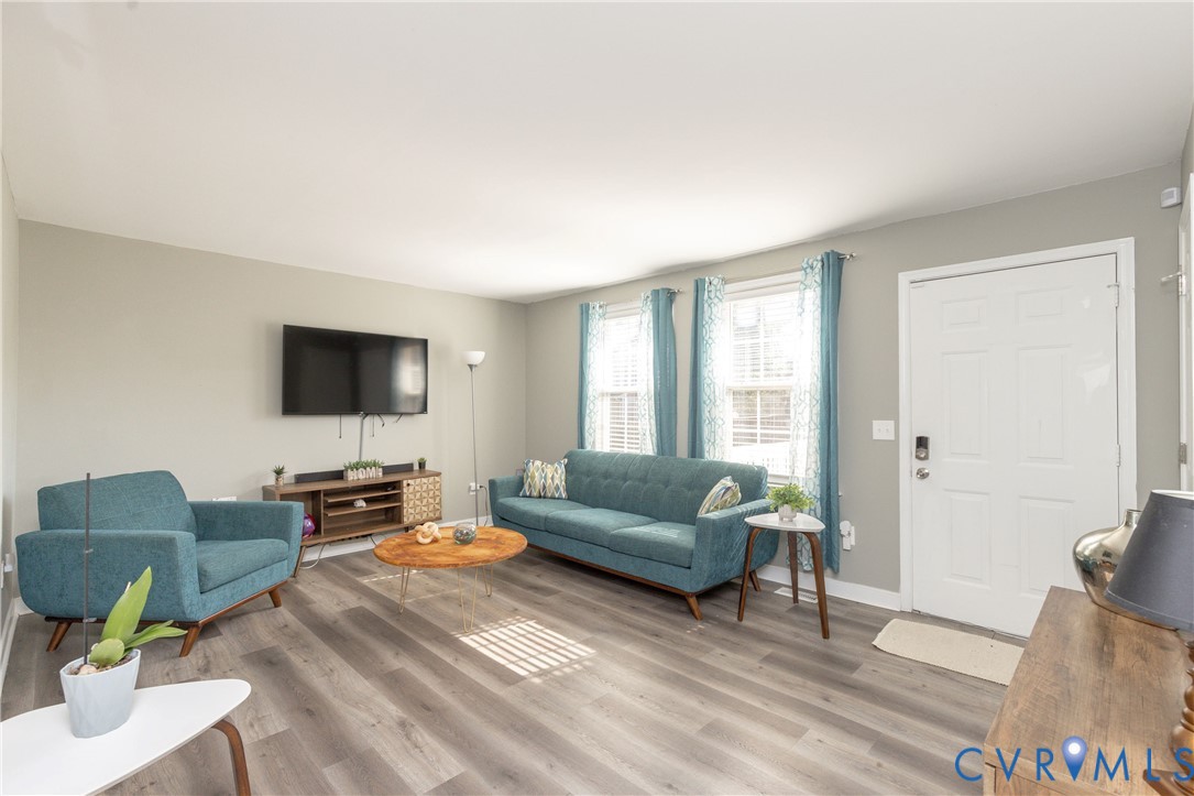 Living area featuring wood-finish flooring, two multi-pane windows, and a panel-style entry door