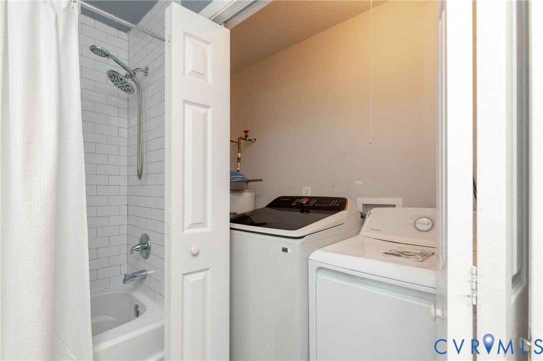 Subway tile shower surround with a dual-head shower fixture, polished chrome hardware, and an integrated laundry closet