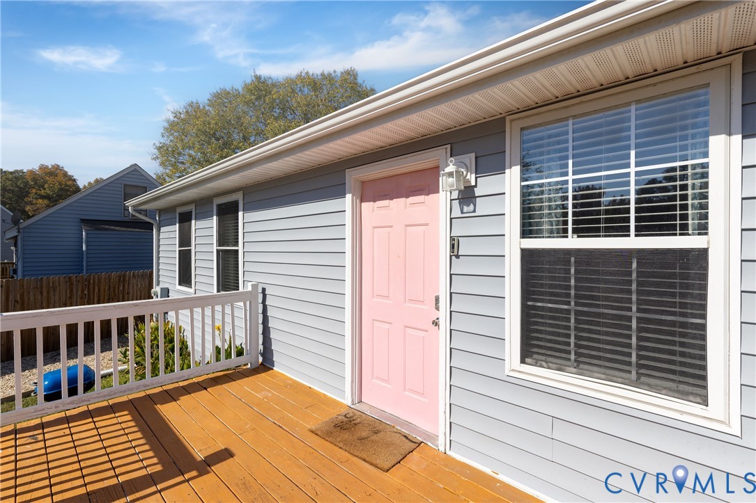 Exterior featuring horizontal lap siding, a wooden deck, a white railing, and a window with white trim