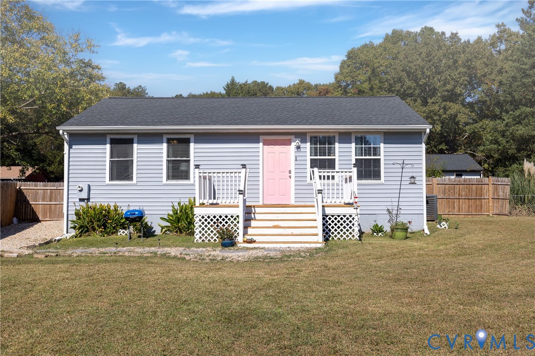 Single-story home featuring light-blue vinyl siding, a dark-tone shingled roof, a wooden front deck with lattice skirting, and a fenced exterior perimeter Single-story home featuring light-blue vinyl siding, a dark-tone shingled roof, a wooden front deck with lattice skirting, and a fenced exterior perimeter
