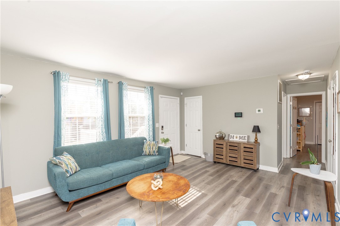 Neutral-toned interior space featuring wood-finish flooring, dual windows with multi-pane glazing, and two six-panel doors