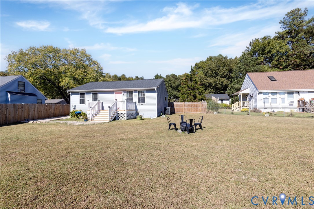 Expansive backyard featuring a large grass lawn, perimeter wood fencing, and an elevated rear deck with white railing