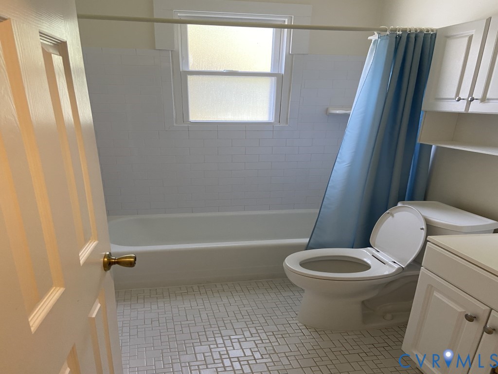 Bathroom featuring white subway tile tub surround, basketweave patterned tile flooring, built-in cabinetry, and a double-hung window