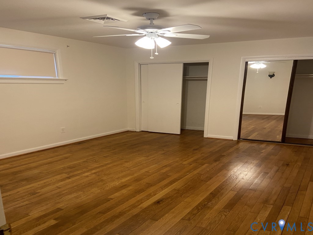 Wood-finish flooring, ceiling fan with integrated lighting, closet with sliding panels, and a closet with mirrored sliding doors