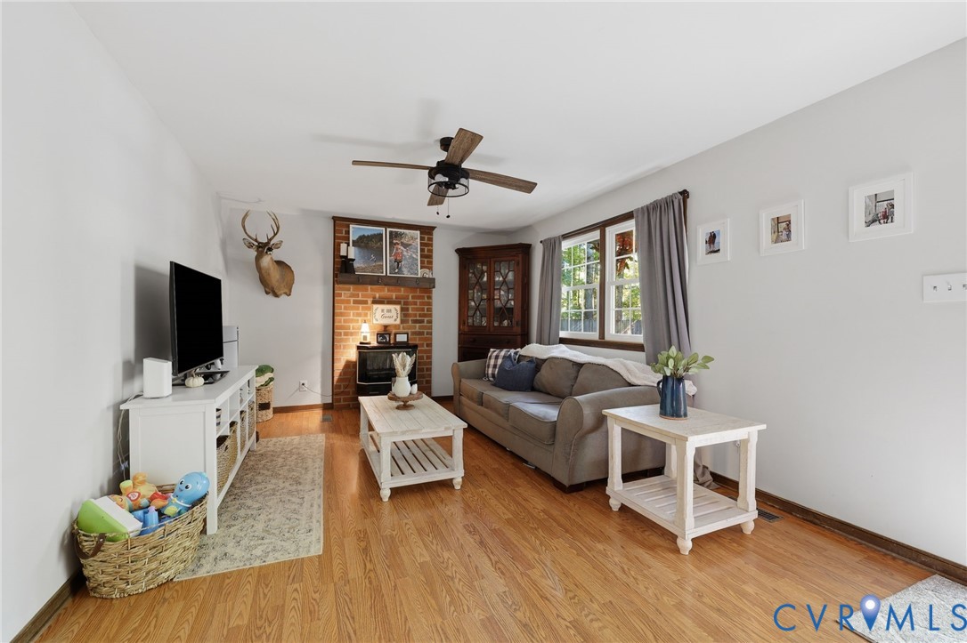 Featuring a floor-to-ceiling brick fireplace with a wood mantel, and ceiling fan