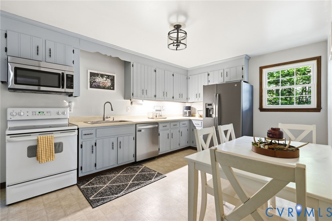 Kitchen featuring light-toned cabinetry, SS Dishwasher, neutral countertops, a single-basin sink with a gooseneck faucet, and overhead lantern-style lighting