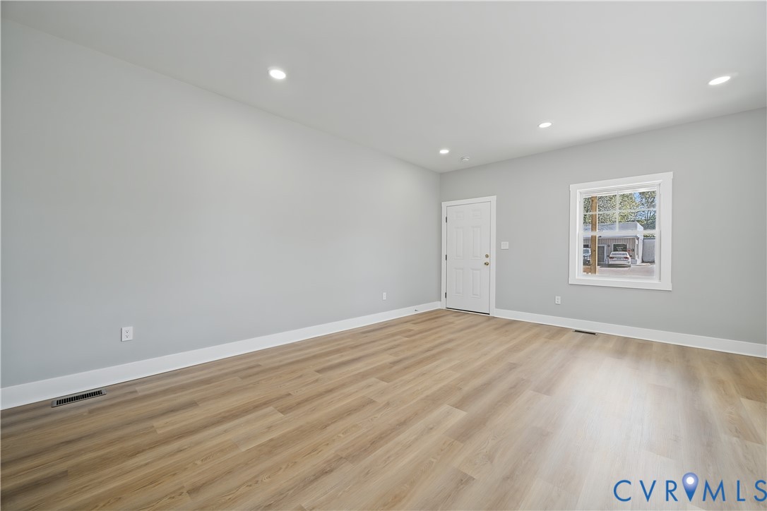 Neutral-toned interior space featuring wood-finish flooring, recessed lighting, and a single-hung window with white casing
