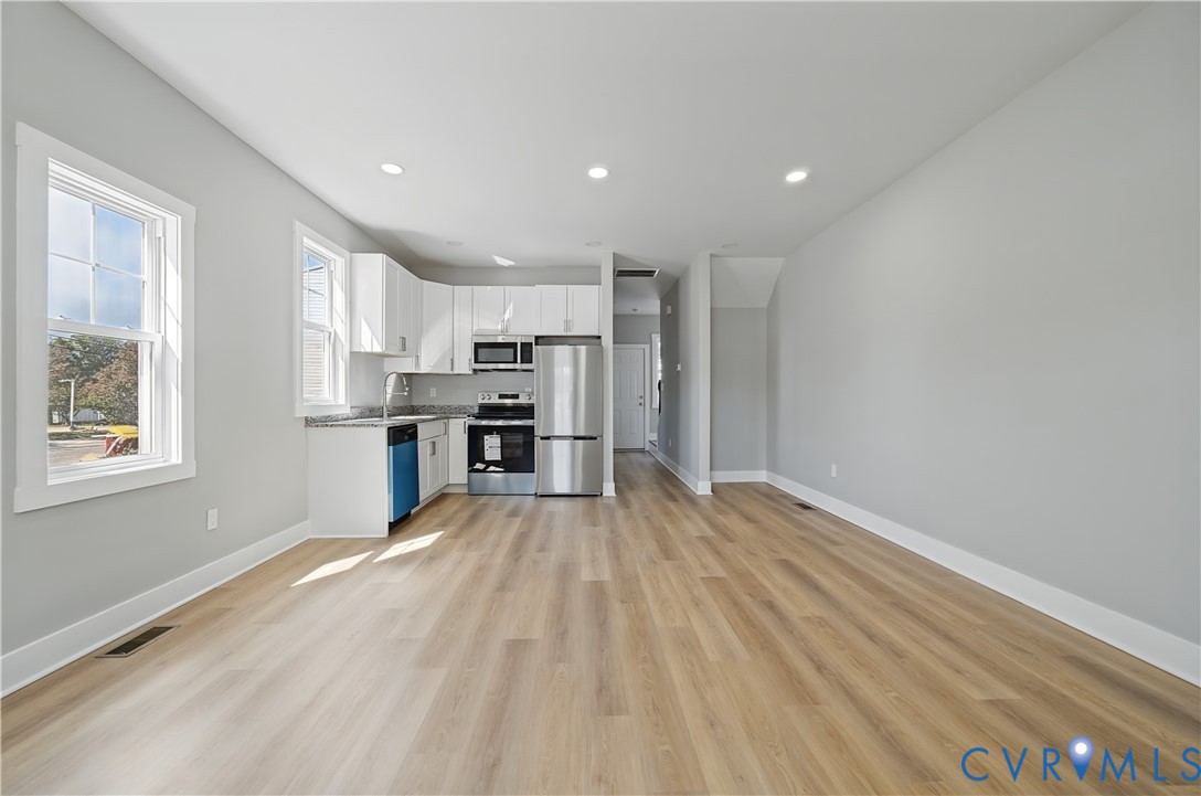 Kitchen featuring white cabinetry, stone-finish countertops, stainless steel appliances, recessed lighting, and wood-finish flooring
