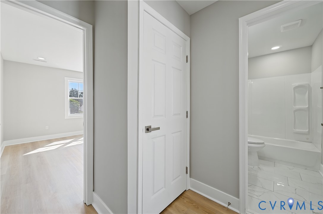 Neutral grey walls, six-panel interior door with brushed metal hardware, and wood-finish flooring