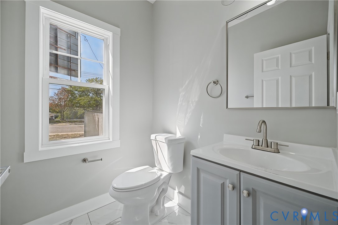 Vanity with gray cabinetry and an integrated sink, polished chrome faucet, rectangular wall mirror, and tile flooring