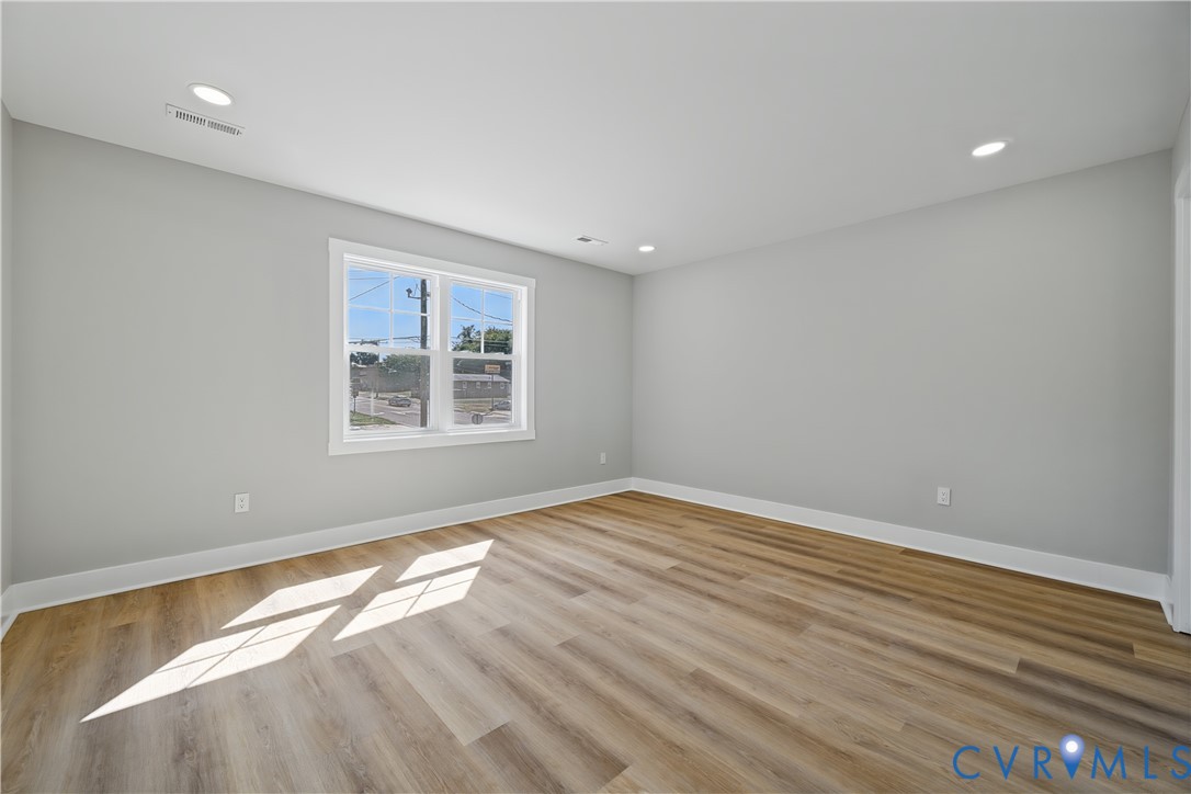 Neutral interior space featuring wood-finish flooring, recessed lighting, and a multi-pane window