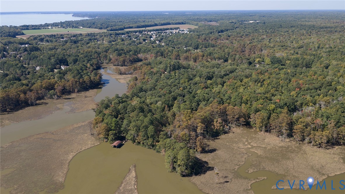 Aerial expanse featuring tidal marshland, wooded acreage, and a private boat slip