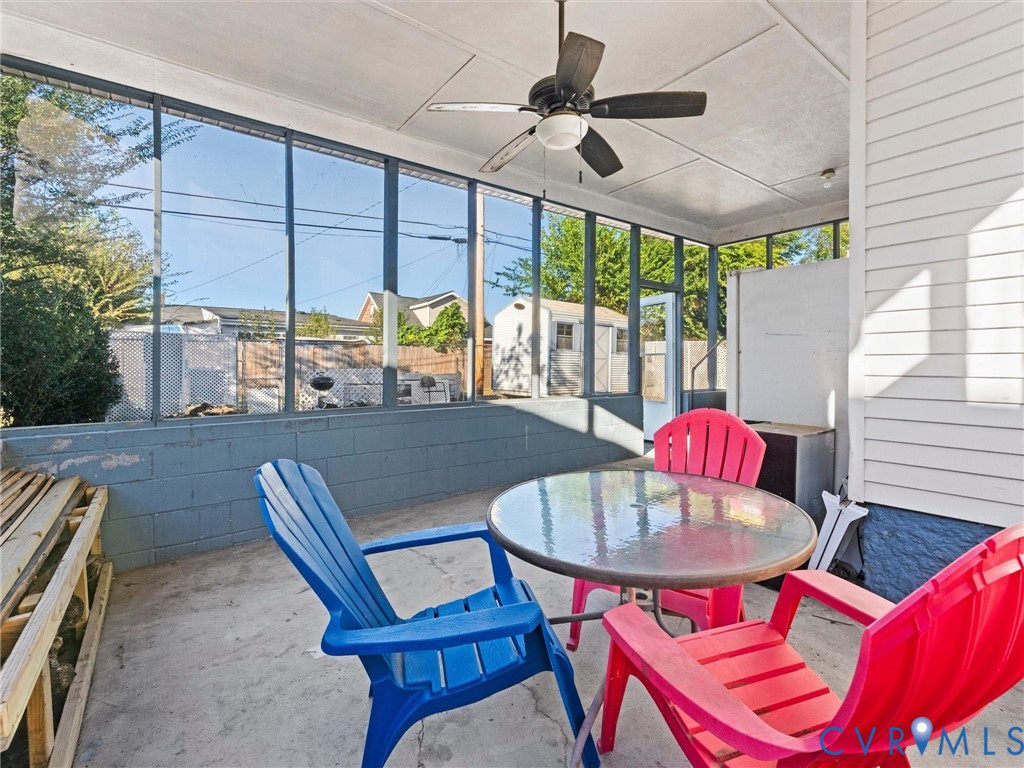 Screened-in porch featuring a concrete floor, painted masonry walls, and a ceiling-mounted fan