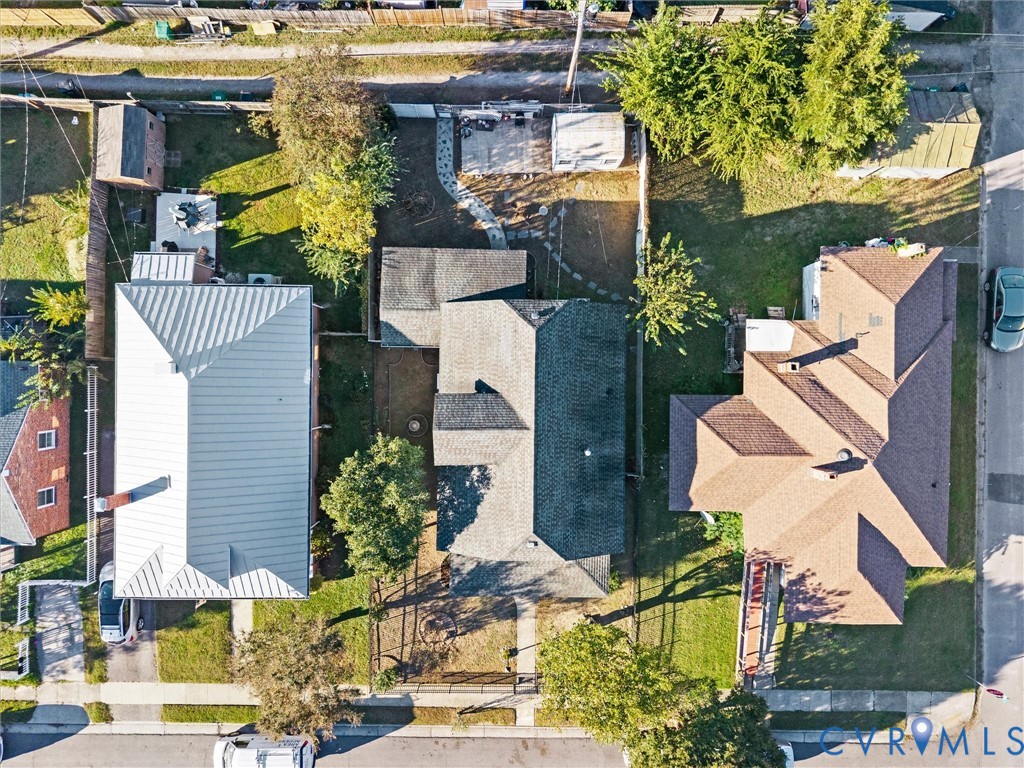 Aerial view featuring roof, backyard with  paved stone path, detached shed, and perimeter fencing