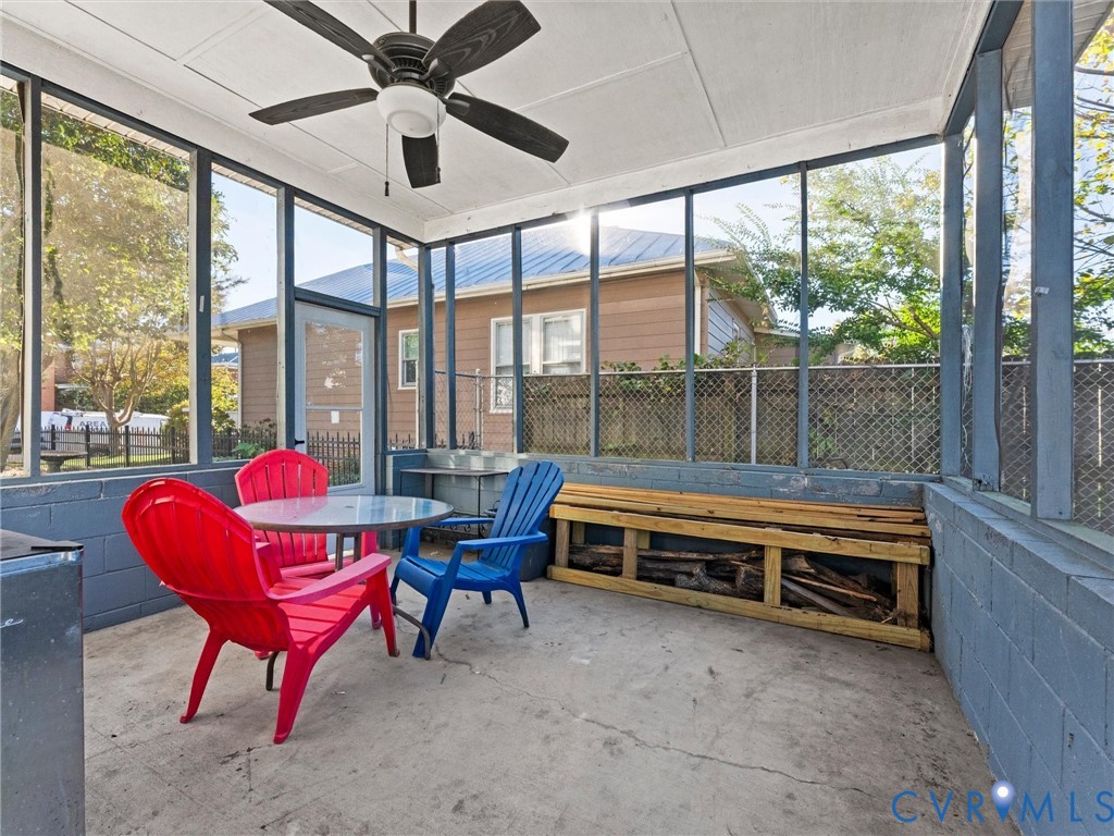 Screened-in porch featuring painted masonry walls, a concrete floor, and an overhead ceiling fan