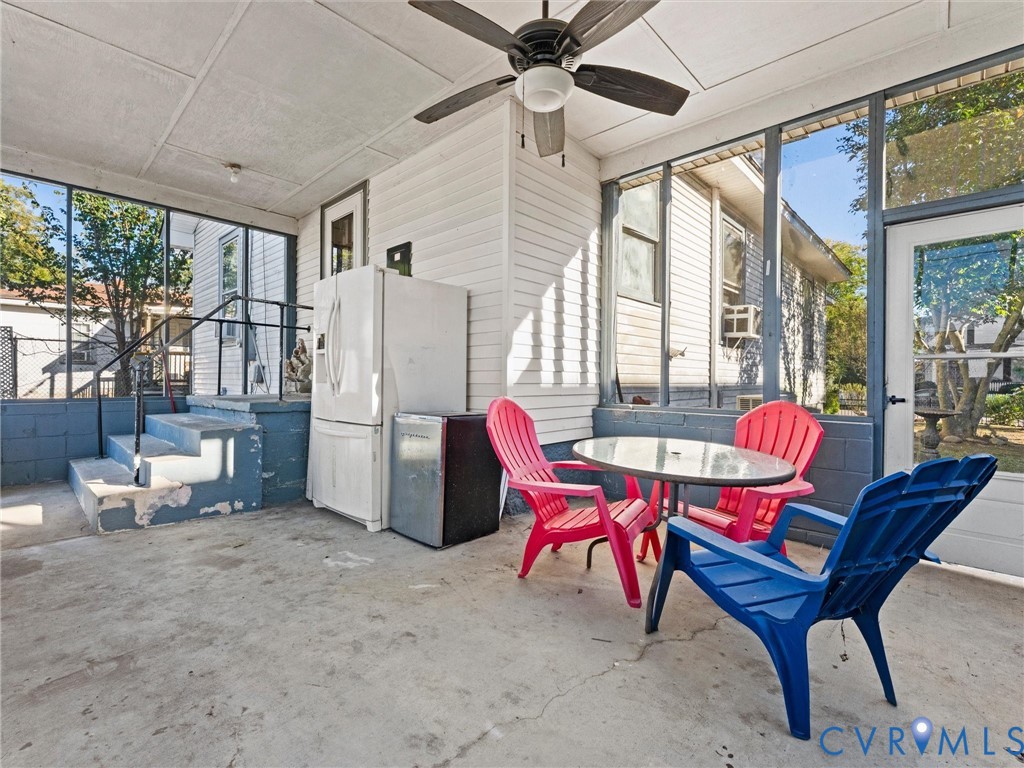 Screened-in porch featuring concrete flooring, and a ceiling fan