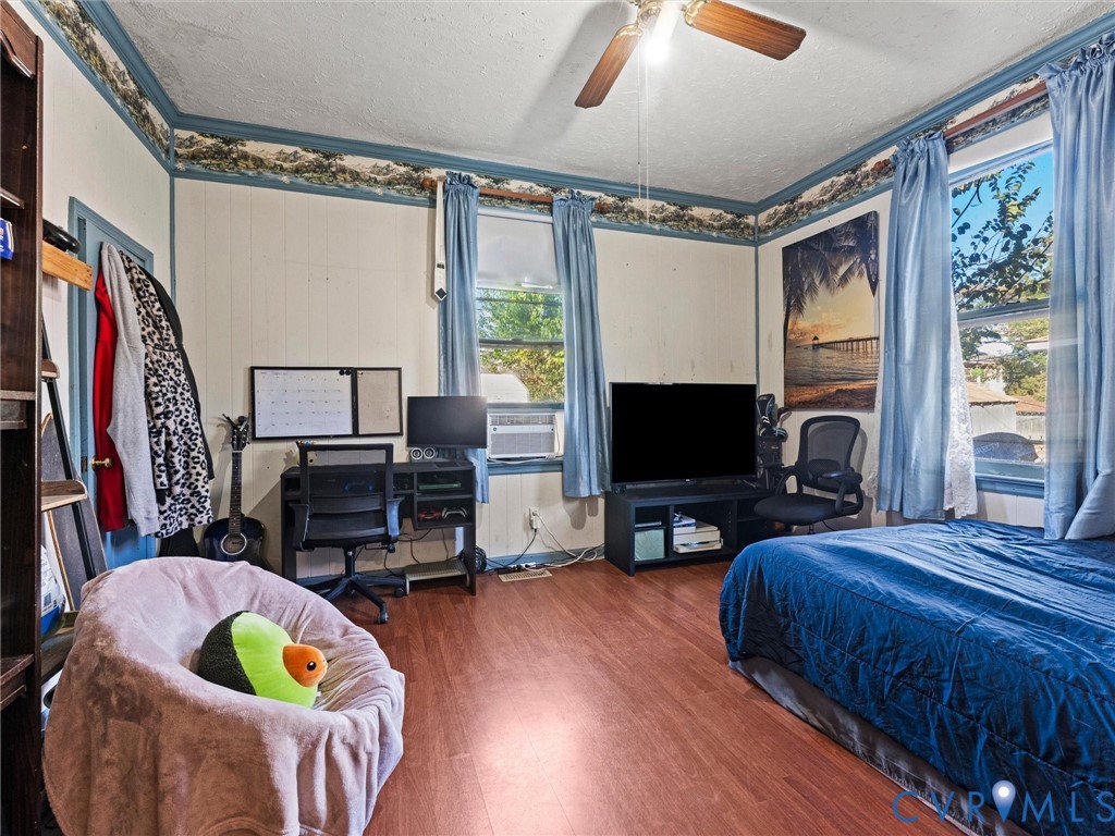 Bedroom featuring wood-finish flooring, dual windows, and a ceiling fan