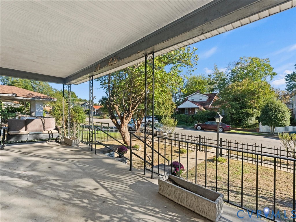Covered concrete front porch featuring ornamental metal railings and posts