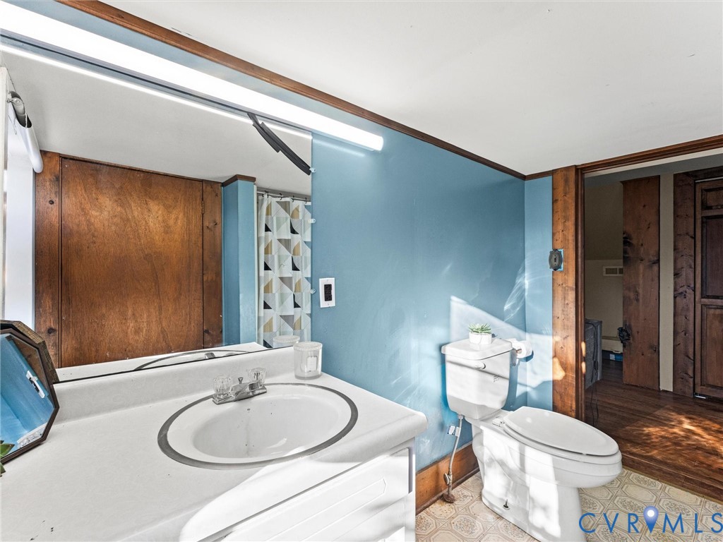 Bathroom featuring a white vanity with an integrated oval basin, a full-width wall-mounted mirror, and patterned resilient flooring