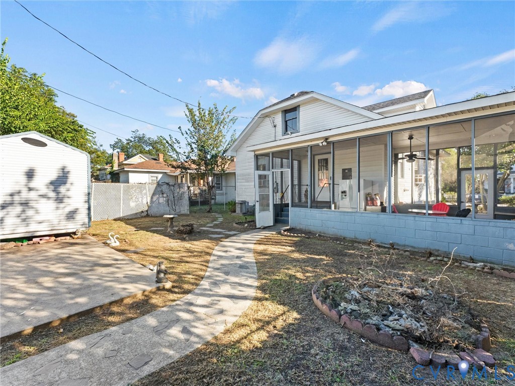Exterior space featuring a large screened-in porch with a concrete block foundation, a flagstone-style pathway, a detached storage shed