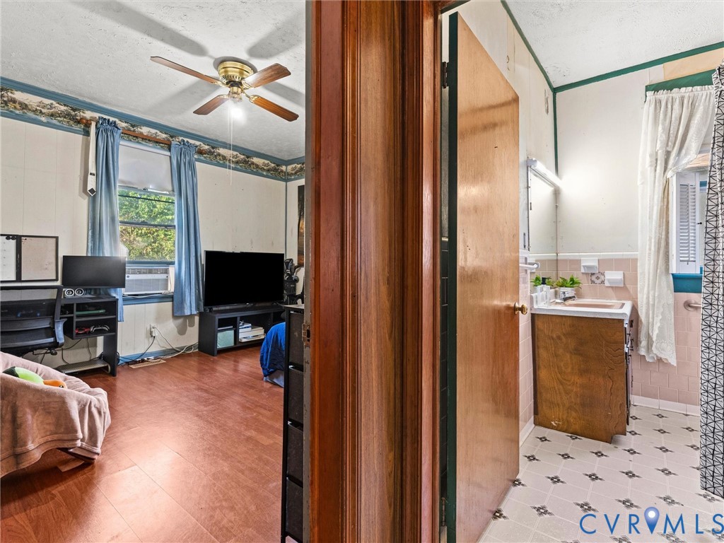 Wood-finish flooring, ceiling fan, solid wood door, built-in bathroom vanity, and vinyl floor